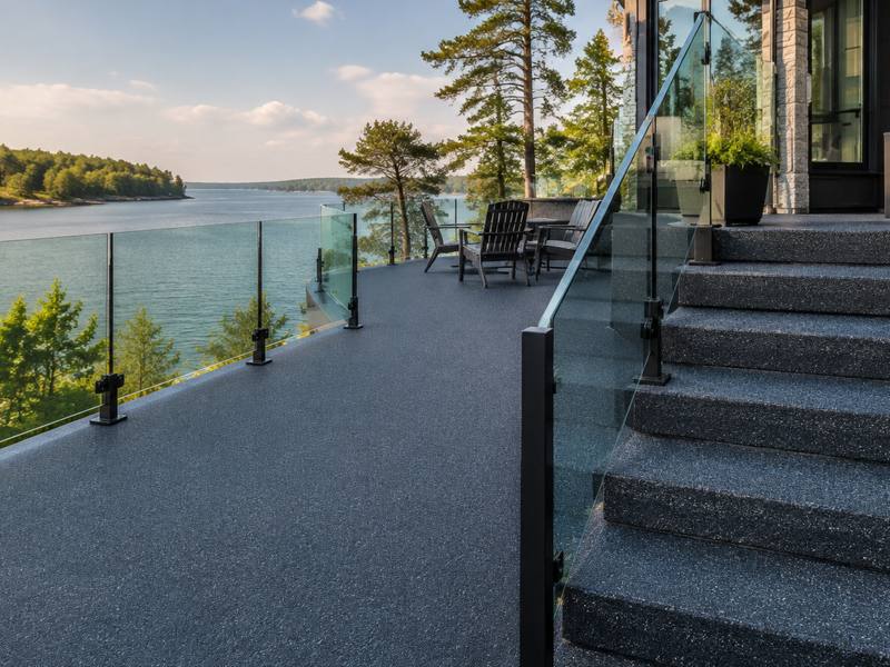 Waterfront terrace with glass railings and rubber surfaced stairs leading down toward the lake