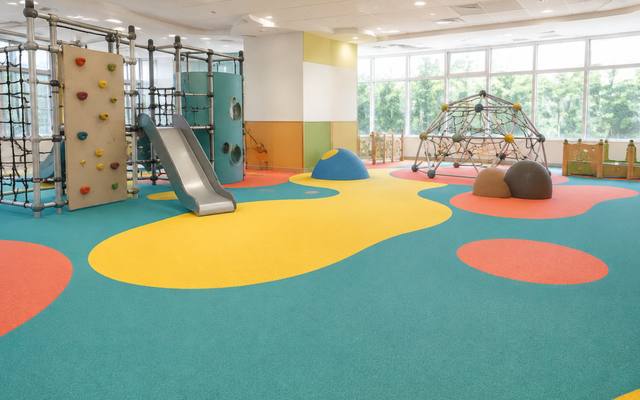 Indoor play centre with a climbing wall on yellow, red and teal rubber surfacing